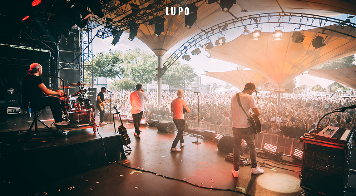 Eine Band spielt bei einem Open-Air-Konzert vor zahlreichem Publikum.