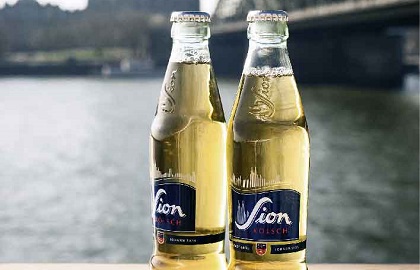 Zwei volle Bierflaschen stehen nebeneinander vor einem Fluss.