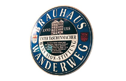 Rundes blaues Schild mit goldener und weißer Schrift und einem roten Wappen.