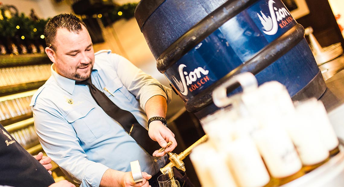 Ein Mann füllt ein Bierglas aus einem Fass auf einer Theke.