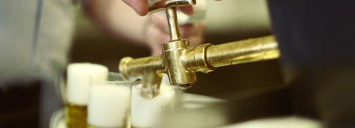 Ein goldener Zapfhahn füllt Flüssigkeit in mehrere Gläser.